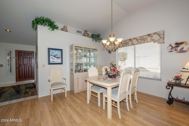 dining area featuring light hardwood / wood-style floors, lofted ceiling, and an inviting chandelier