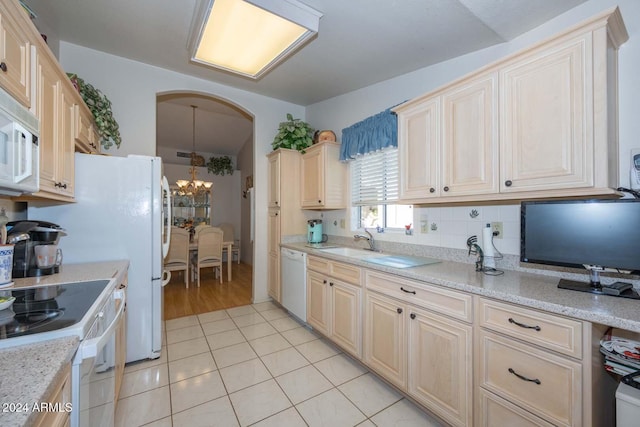 kitchen with light stone countertops, a chandelier, decorative light fixtures, white appliances, and light tile patterned floors