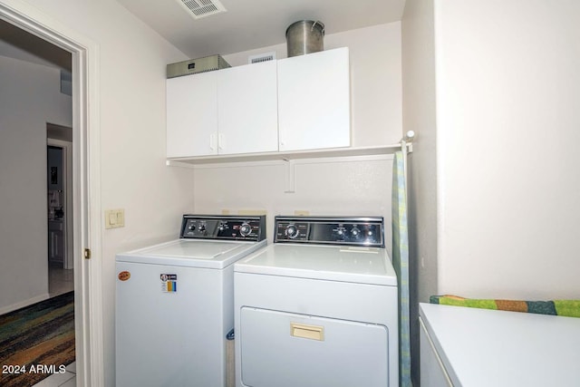 laundry room featuring washer and dryer and cabinets