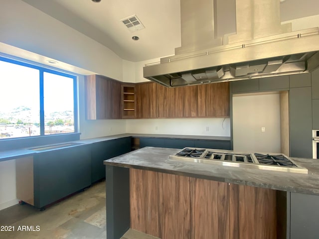 kitchen with stainless steel gas stovetop, dark stone countertops, and island exhaust hood