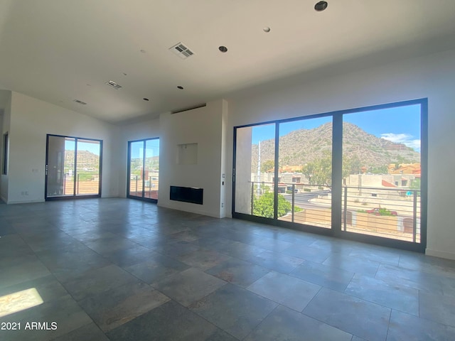 unfurnished living room with a wealth of natural light, a mountain view, and vaulted ceiling