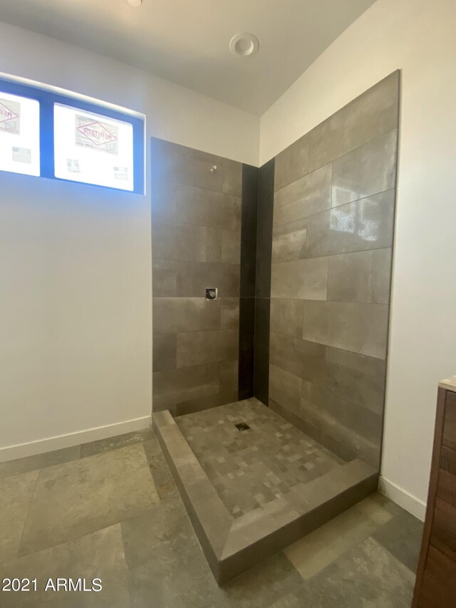 bathroom with a tile shower and vanity