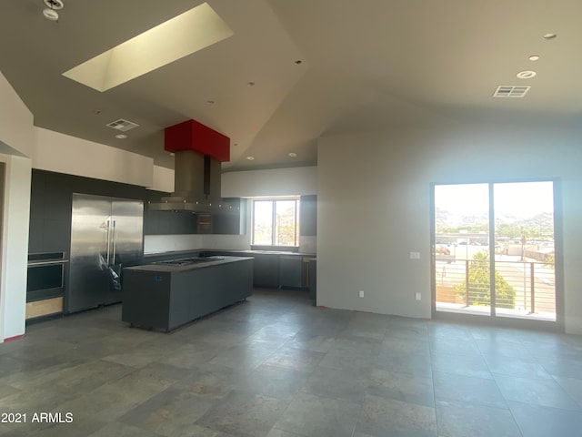 kitchen with a skylight, a center island, gas stovetop, high quality fridge, and high vaulted ceiling