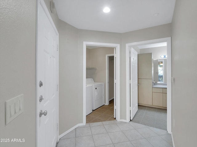 hall featuring light tile patterned flooring, visible vents, washing machine and dryer, and baseboards