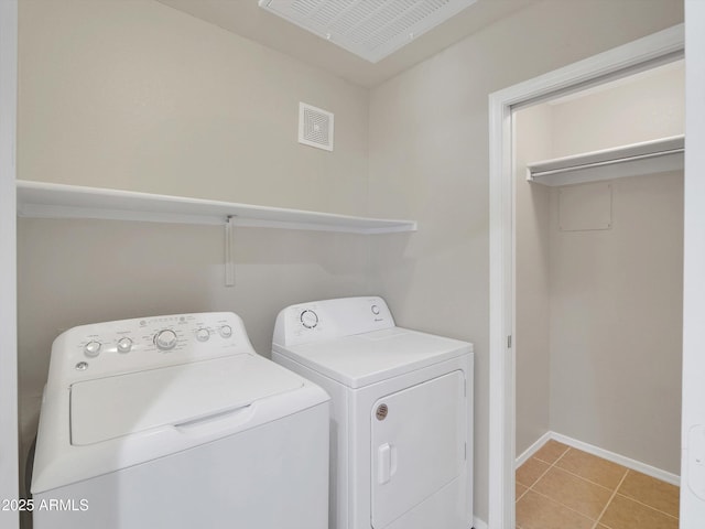 washroom featuring baseboards, separate washer and dryer, light tile patterned flooring, and laundry area