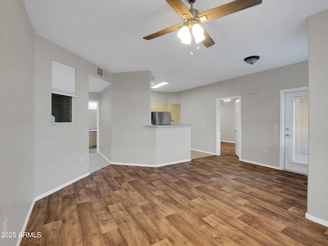 unfurnished living room with visible vents, light wood-style floors, baseboards, and ceiling fan