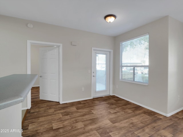 unfurnished dining area featuring wood finished floors and baseboards