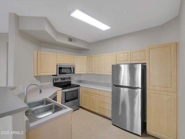 kitchen with visible vents, light brown cabinets, stainless steel appliances, and a sink