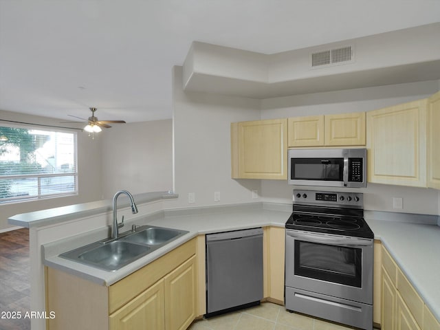 kitchen with visible vents, light brown cabinets, a peninsula, stainless steel appliances, and a sink