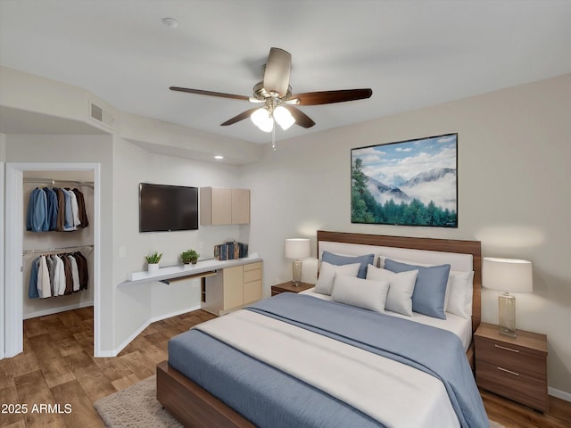 bedroom with wood finished floors, visible vents, baseboards, a spacious closet, and a closet