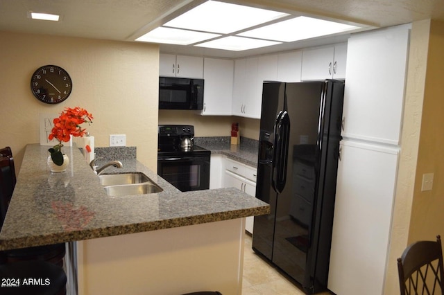 kitchen with a breakfast bar area, a peninsula, a sink, white cabinetry, and black appliances