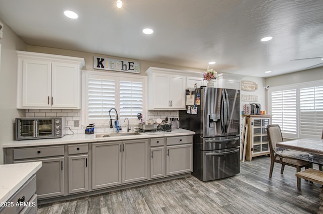 kitchen with light wood-type flooring, gray cabinets, light countertops, and stainless steel refrigerator with ice dispenser