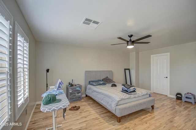 bedroom featuring baseboards, visible vents, ceiling fan, and wood finished floors