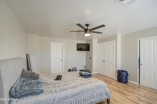 bedroom with light wood-style flooring, a ceiling fan, visible vents, baseboards, and a closet