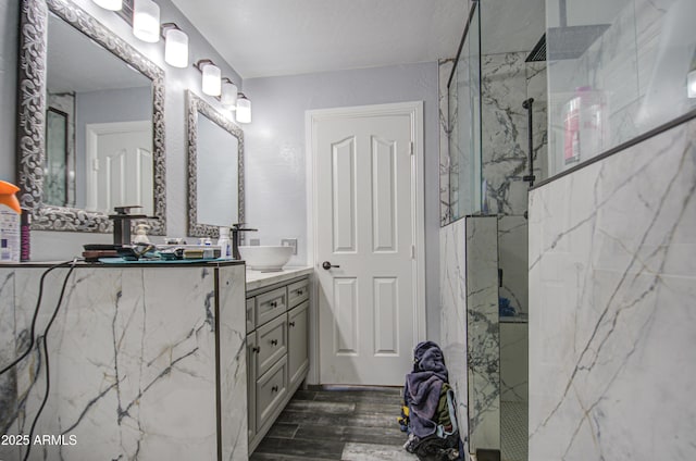 bathroom with a marble finish shower, wood finished floors, and vanity