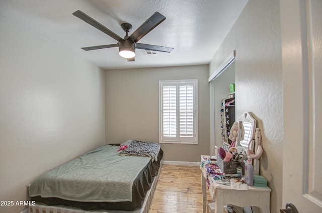 bedroom featuring ceiling fan, baseboards, visible vents, and light wood-style floors