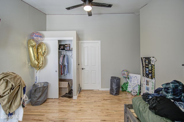 bedroom with light wood-style flooring, ceiling fan, and a closet