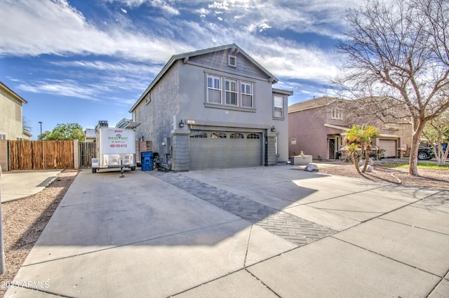 traditional-style home with an attached garage, driveway, fence, and stucco siding