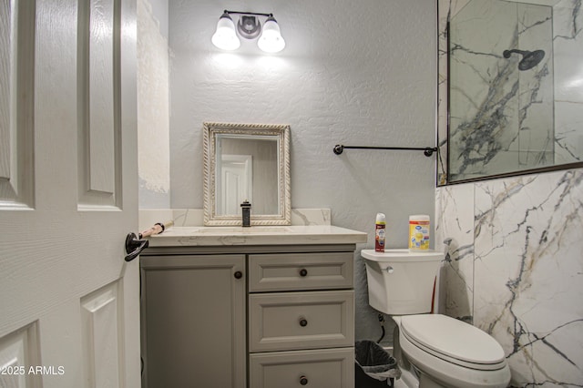 bathroom with a textured wall, vanity, and toilet