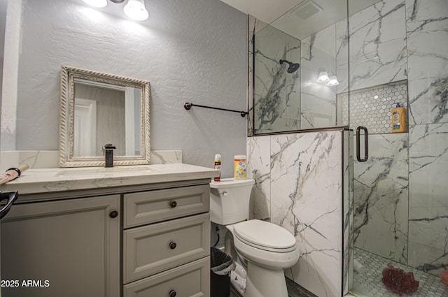 bathroom featuring toilet, a marble finish shower, vanity, and a textured wall