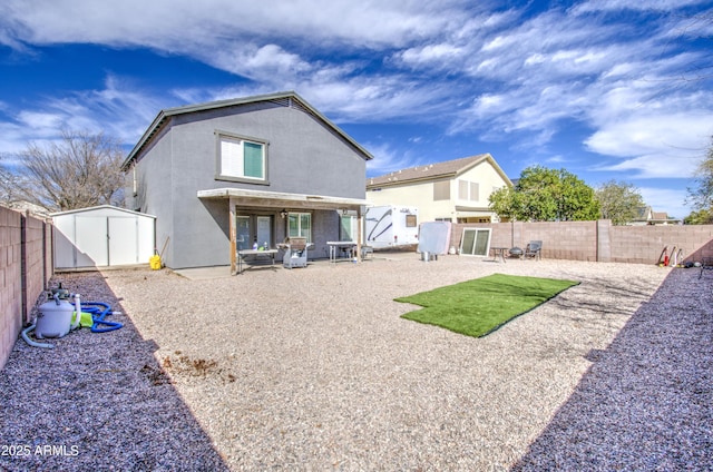 rear view of house featuring stucco siding, a storage shed, a patio area, a fenced backyard, and an outdoor structure