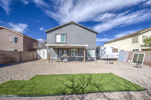 rear view of house with a patio, fence, a storage unit, an outdoor structure, and stucco siding