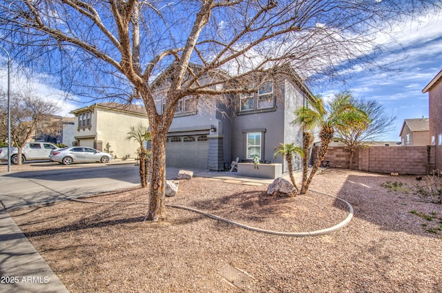 view of front of property with driveway, fence, an attached garage, and stucco siding