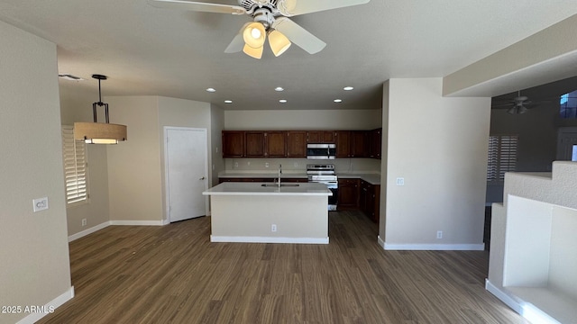 kitchen featuring decorative light fixtures, stainless steel appliances, a kitchen island with sink, dark hardwood / wood-style flooring, and sink