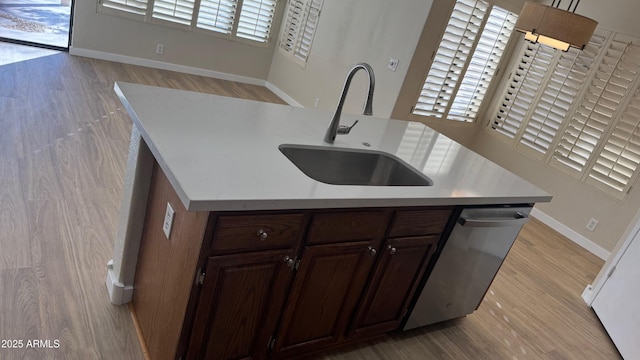 kitchen with sink, light hardwood / wood-style floors, dishwasher, and a center island with sink