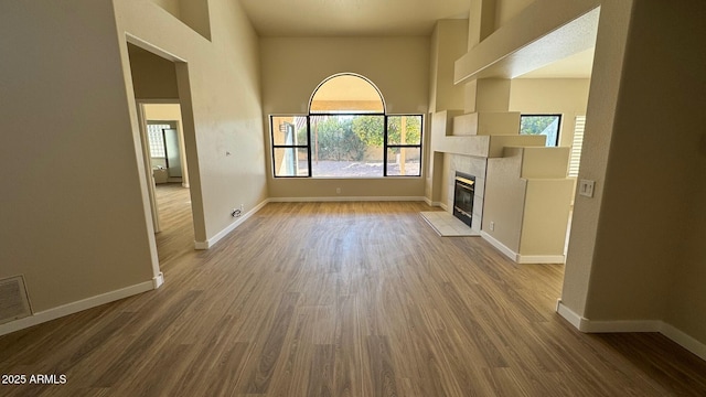 unfurnished living room featuring a tiled fireplace and wood-type flooring