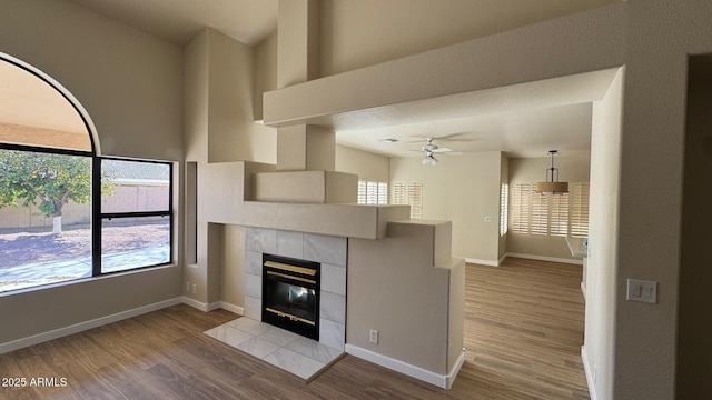 unfurnished living room with a tile fireplace, ceiling fan, and light hardwood / wood-style floors