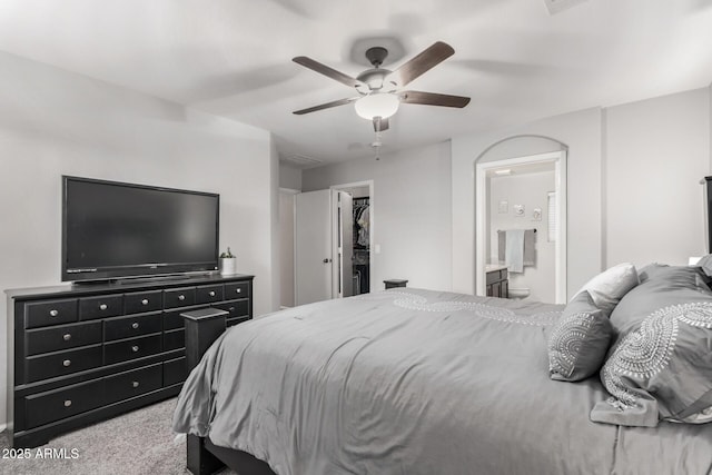 carpeted bedroom featuring ensuite bath, ceiling fan, a closet, and a walk in closet