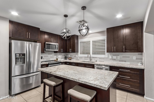 kitchen featuring a center island, sink, light tile patterned floors, decorative light fixtures, and stainless steel appliances