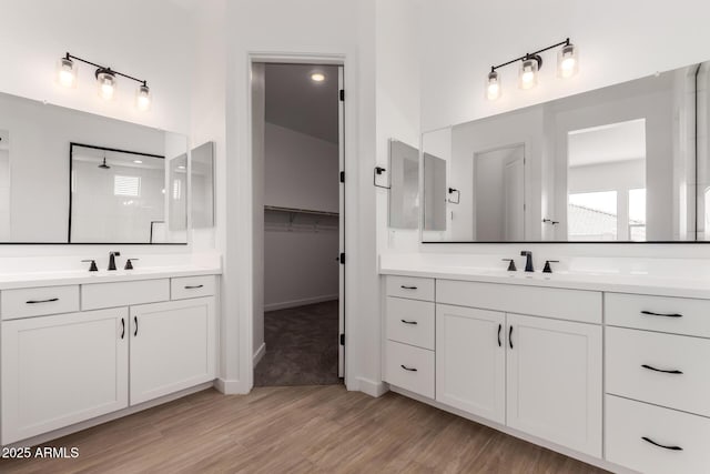 20273 W Monterey Way, Buckeye, AZ 85396 - bathroom with two vanities, wood finished floors, a tile shower, and a walk in closet