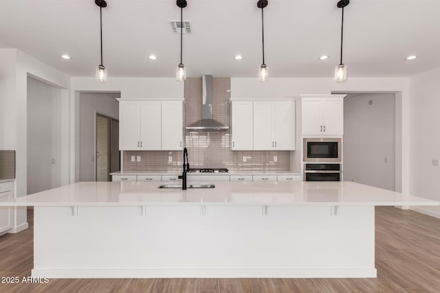 20273 W Monterey Way, Buckeye, AZ 85396 - kitchen with black appliances, wall chimney exhaust hood, decorative backsplash, a spacious island, and recessed lighting