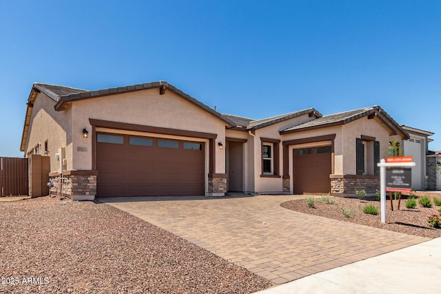 20273 W Monterey Way, Buckeye, AZ 85396 - ranch-style house featuring a garage, stone siding, stucco siding, and driveway