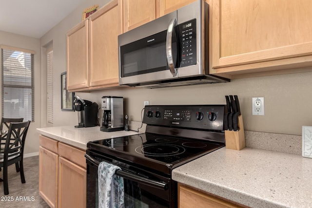 kitchen featuring baseboards, light brown cabinets, stainless steel microwave, and black electric range oven