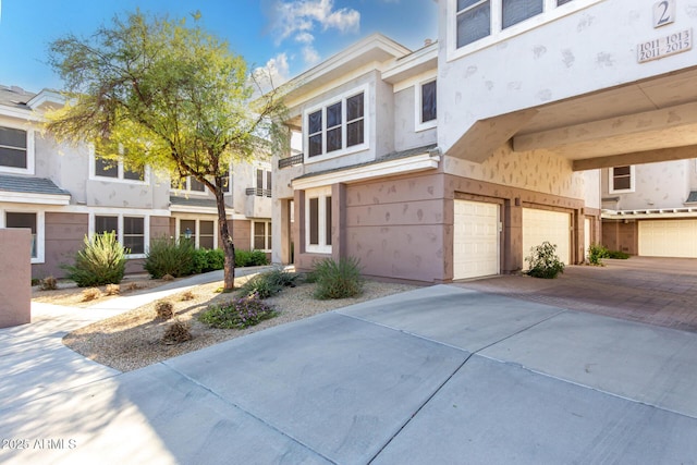 view of property with a garage, driveway, and stucco siding