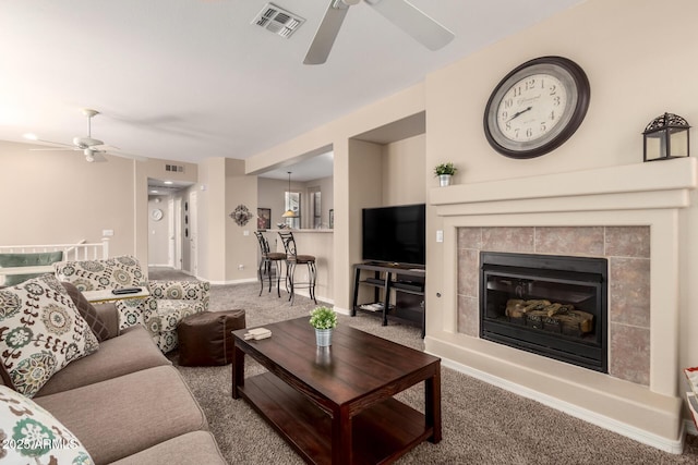 living room featuring a ceiling fan, carpet flooring, visible vents, and a tiled fireplace