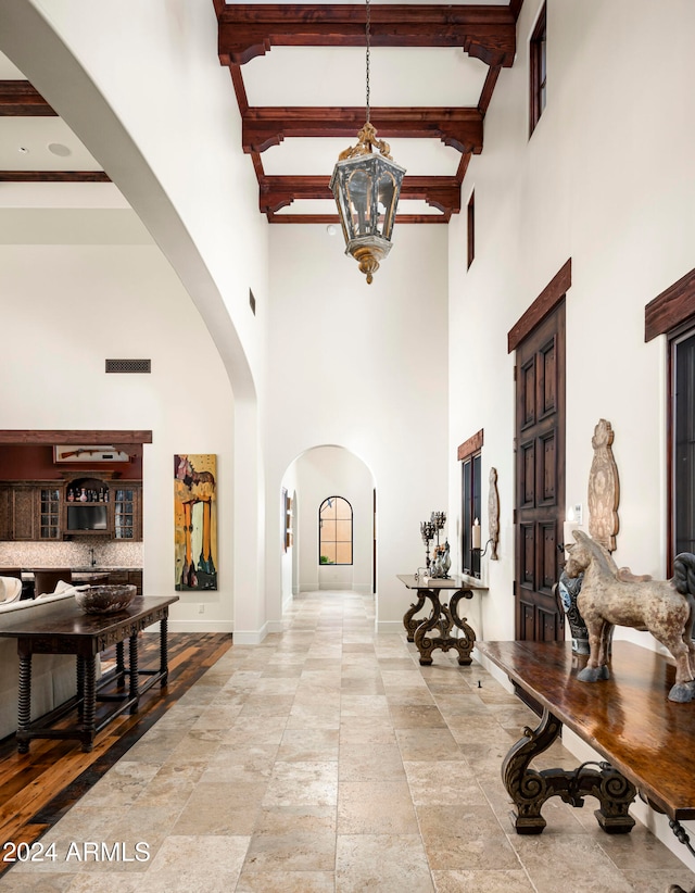 interior space featuring beamed ceiling, a notable chandelier, and a towering ceiling