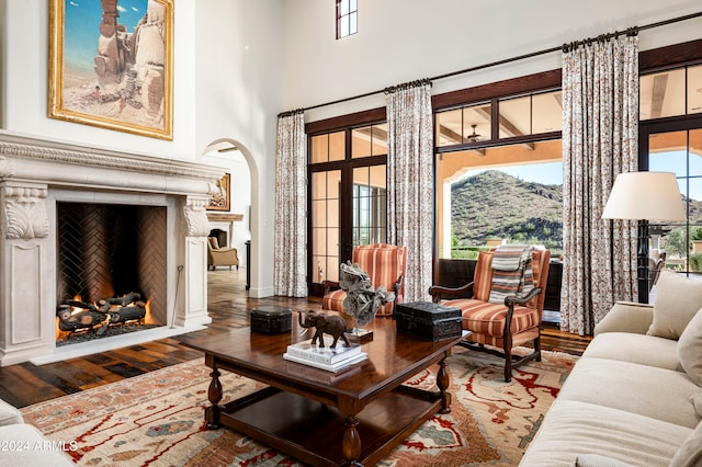 living room with hardwood / wood-style floors, a mountain view, and a towering ceiling