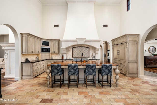 kitchen featuring black microwave, sink, a high ceiling, tasteful backsplash, and a kitchen breakfast bar