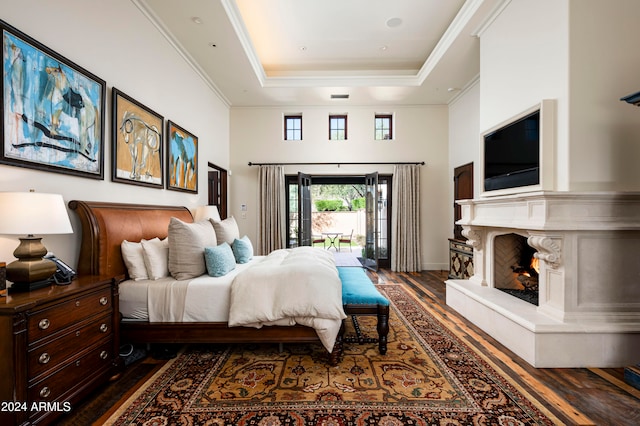 bedroom with ornamental molding, dark wood-type flooring, access to outside, and a tray ceiling