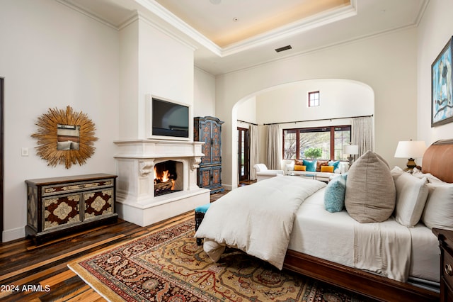 bedroom featuring ornamental molding, a tray ceiling, and dark wood-type flooring