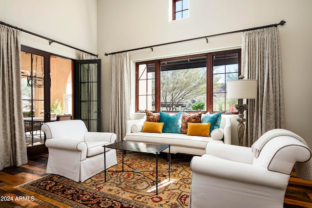 living room featuring french doors, a towering ceiling, and hardwood / wood-style flooring