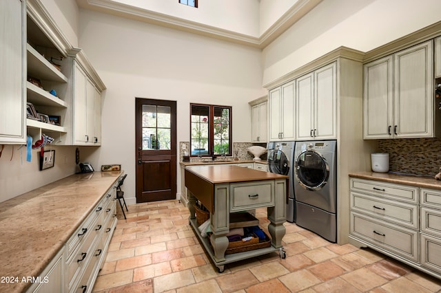 clothes washing area featuring cabinets, a high ceiling, and washer and dryer