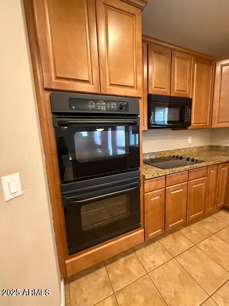 kitchen featuring light tile patterned flooring, stone countertops, and black appliances