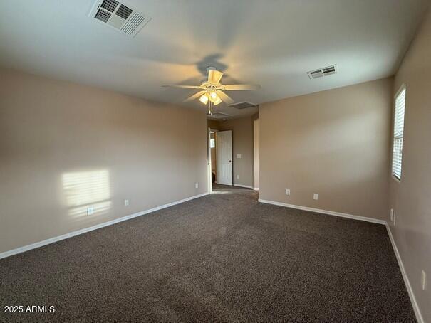 empty room with ceiling fan and dark colored carpet