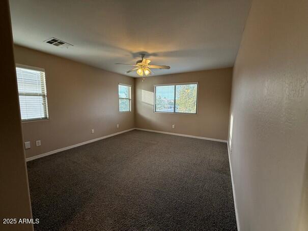 empty room with ceiling fan and dark carpet