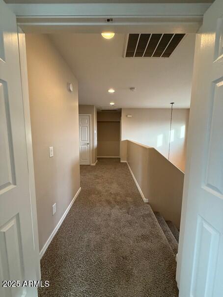 hallway featuring dark colored carpet